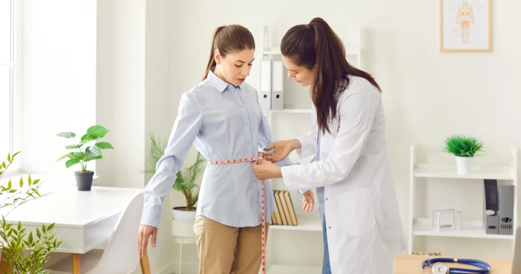 Medical professional measuring a patient’s waist in a bright, modern clinic, highlighting a Medically Guided Weight Loss Program in Walnut Creek, CA.